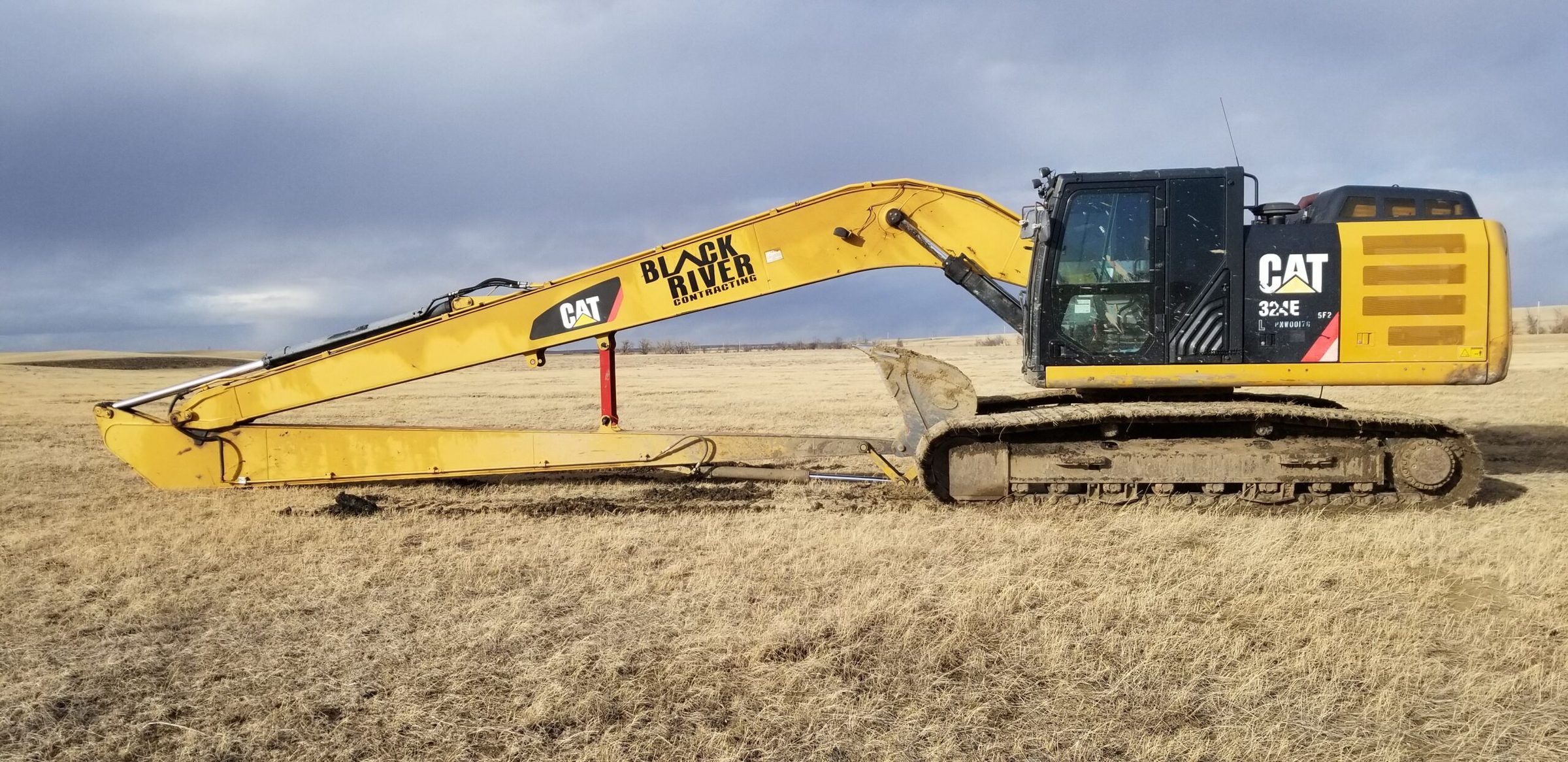 Black River long-reach excavator working from the bank in open rangeland