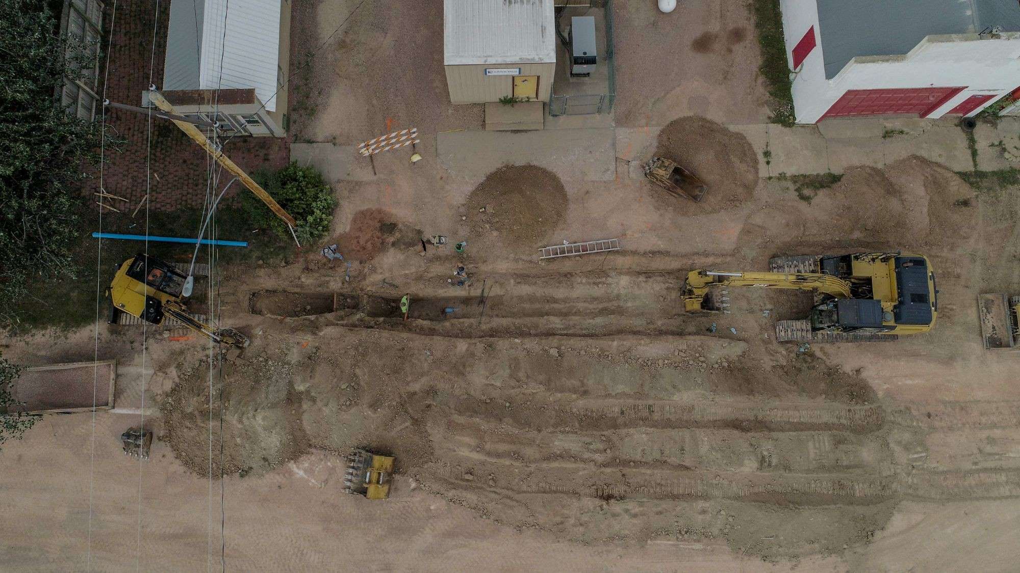 Overhead view of a Black River crew working in a water line trench between two excavators