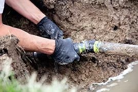 Worker connecting a water service line in an open trench